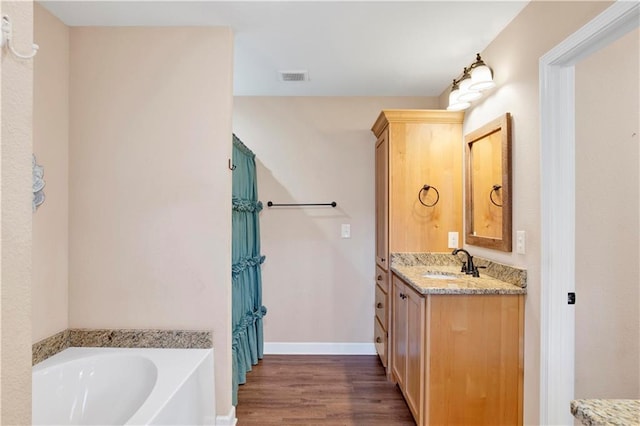 bathroom featuring hardwood / wood-style flooring, vanity, and a bath