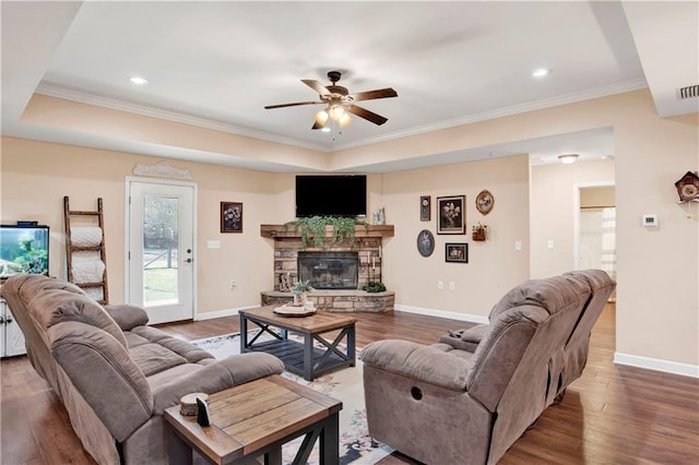 living room featuring ceiling fan, a stone fireplace, dark hardwood / wood-style flooring, and crown molding