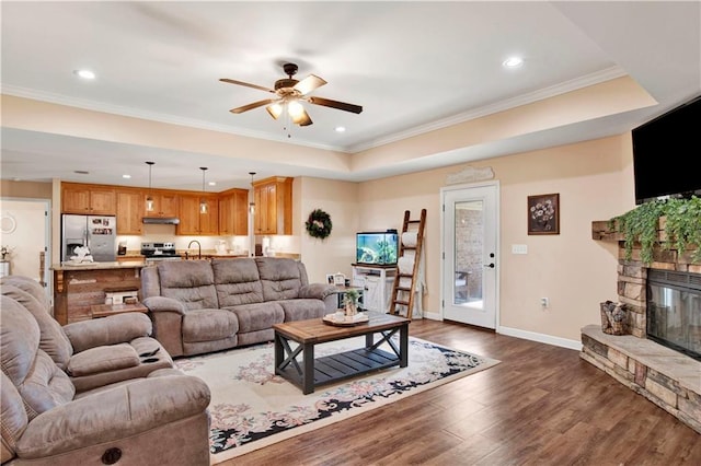 living room with a tray ceiling, ceiling fan, crown molding, and dark hardwood / wood-style floors