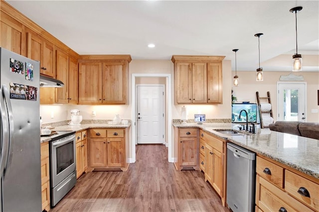 kitchen featuring light stone countertops, sink, stainless steel appliances, pendant lighting, and wood-type flooring