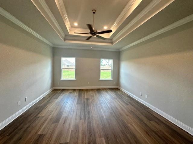 spare room with a tray ceiling, ceiling fan, dark hardwood / wood-style flooring, and crown molding