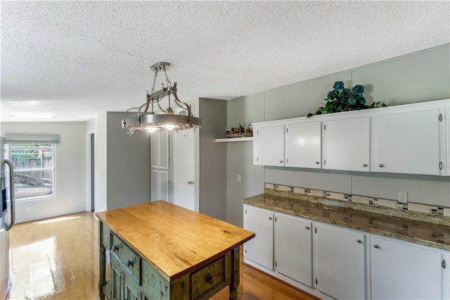 3628 Jarvis Ln, Semmes, AL 36575 - kitchen with wood finished floors, a textured ceiling, white cabinetry, wooden counters, and decorative light fixtures