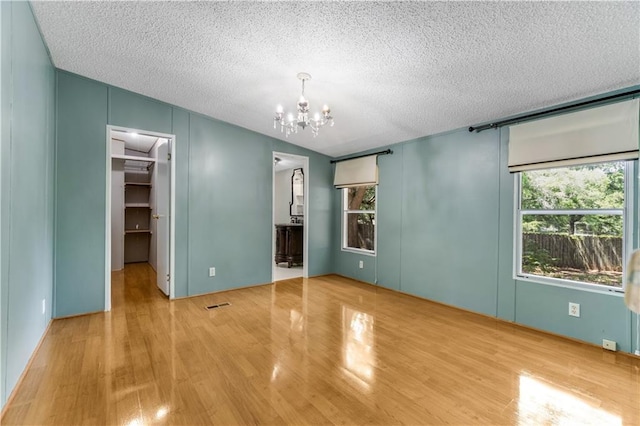 3628 Jarvis Ln, Semmes, AL 36575 - unfurnished bedroom with wood finished floors, a spacious closet, a textured ceiling, a chandelier, and a closet