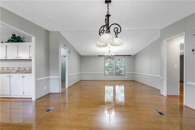 3628 Jarvis Ln, Semmes, AL 36575 - unfurnished dining area with a chandelier, light wood finished floors, and a textured ceiling
