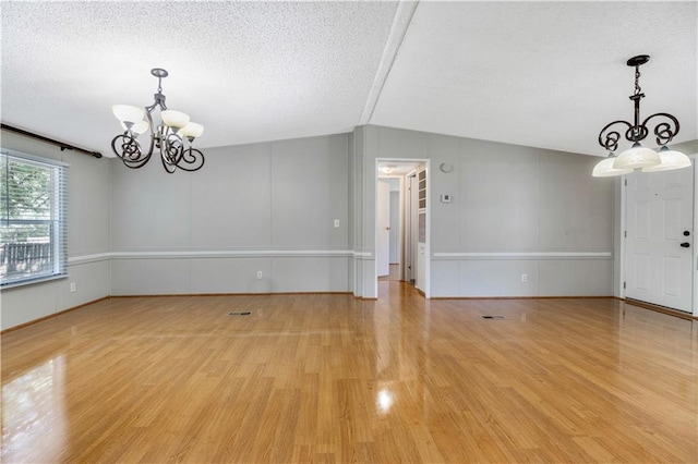 3628 Jarvis Ln, Semmes, AL 36575 - unfurnished room featuring a chandelier, light wood finished floors, a textured ceiling, and vaulted ceiling