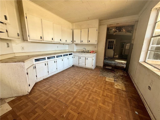 kitchen with white cabinets, sink, and light parquet floors