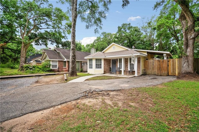 view of front of property featuring fence, brick siding, a chimney, and a porch