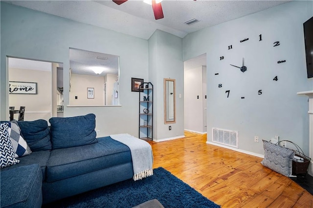 living area featuring a ceiling fan, light wood-type flooring, and baseboards