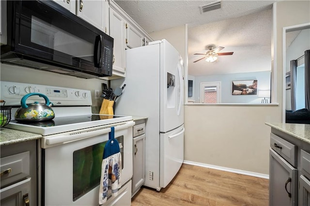 kitchen with white appliances, ceiling fan, light wood-type flooring, light countertops, and a textured ceiling