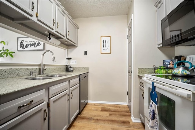 kitchen featuring white range with electric stovetop, black microwave, a sink, stainless steel dishwasher, and light wood finished floors