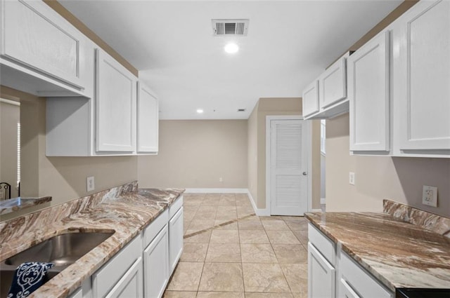 kitchen featuring sink, white cabinetry, light stone counters, and light tile patterned floors