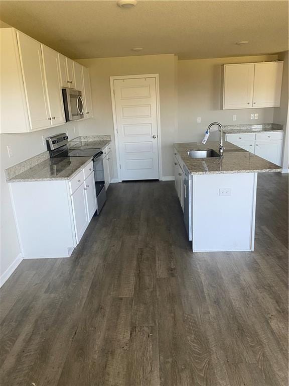 kitchen featuring dark wood-type flooring, light stone counters, appliances with stainless steel finishes, white cabinetry, and a sink