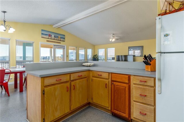 kitchen featuring ceiling fan with notable chandelier, lofted ceiling with beams, light speckled floor, freestanding refrigerator, and light countertops