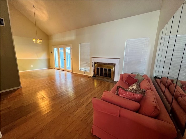 living room with hardwood / wood-style floors, high vaulted ceiling, and a notable chandelier