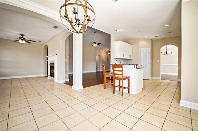 kitchen with arched walkways, light tile patterned floors, ceiling fan with notable chandelier, and open floor plan