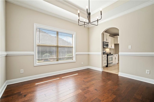 unfurnished dining area featuring a tray ceiling, ornamental molding, an inviting chandelier, hardwood / wood-style flooring, and arched walkways