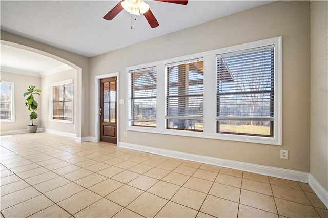 foyer featuring light tile patterned floors, baseboards, arched walkways, and a ceiling fan