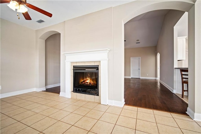 unfurnished living room featuring visible vents, a fireplace, tile patterned flooring, baseboards, and ceiling fan