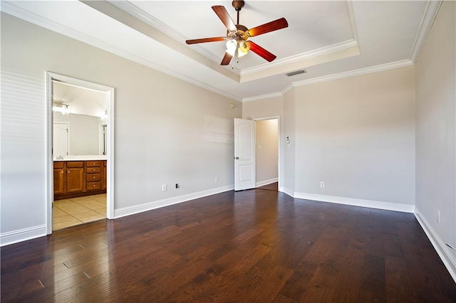 empty room featuring a raised ceiling, hardwood / wood-style flooring, baseboards, and visible vents