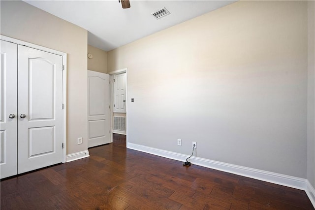 unfurnished bedroom featuring visible vents, baseboards, a closet, and dark wood-style floors