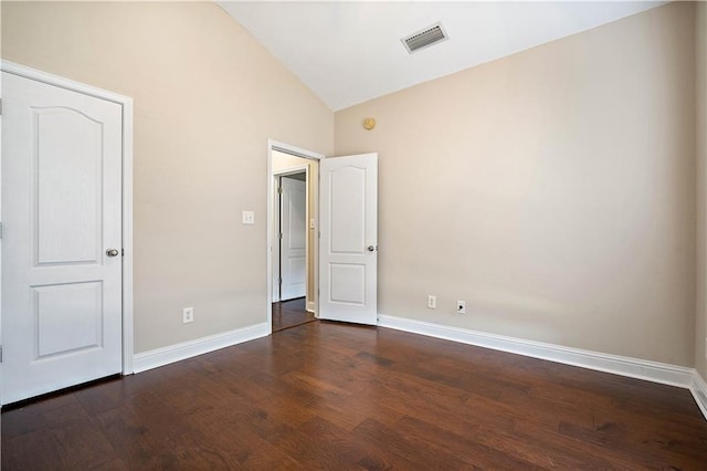 empty room featuring lofted ceiling, baseboards, dark wood-type flooring, and visible vents