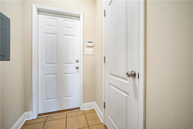 doorway to outside featuring electric panel, light tile patterned floors, and baseboards