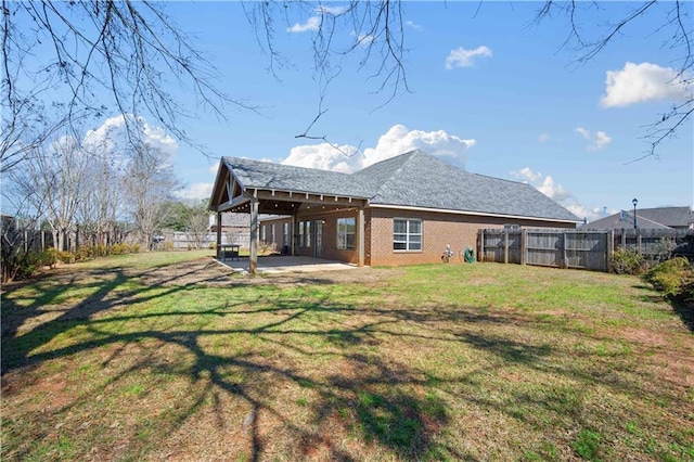 rear view of house with a patio area, a lawn, brick siding, and a fenced backyard