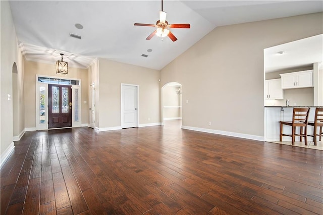 unfurnished living room with visible vents, dark wood-type flooring, arched walkways, baseboards, and ceiling fan