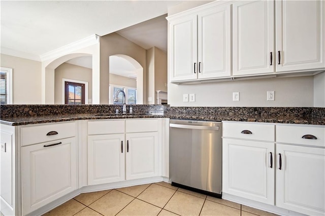 kitchen with light tile patterned floors, white cabinetry, dark stone counters, a sink, and dishwasher