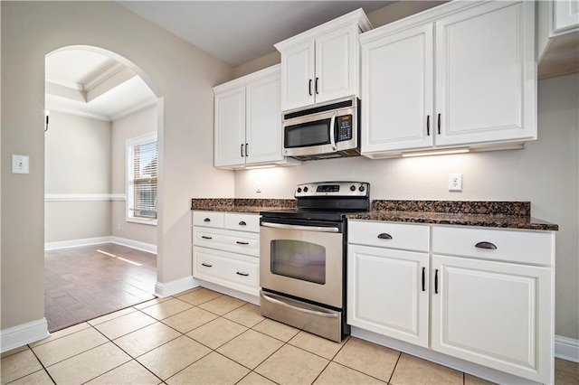 kitchen with stainless steel appliances, arched walkways, light tile patterned flooring, and crown molding