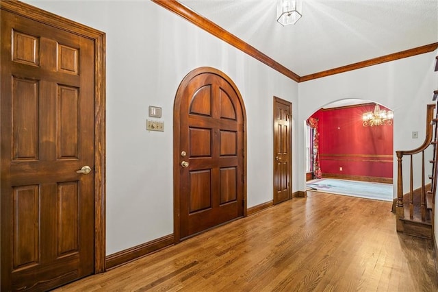 entryway featuring crown molding, a notable chandelier, and wood-type flooring