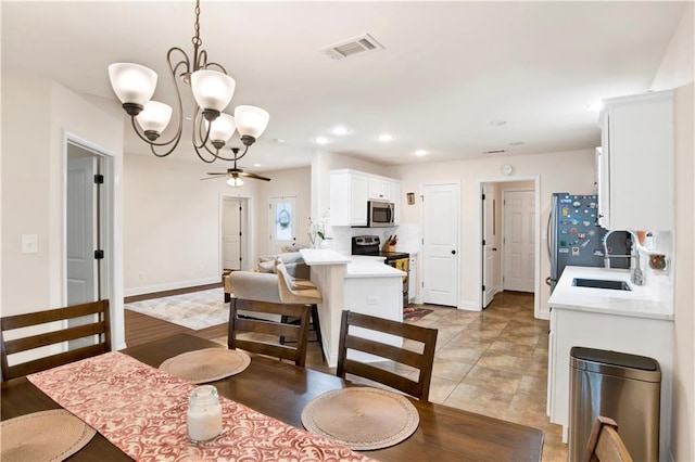 dining space with ceiling fan with notable chandelier, recessed lighting, visible vents, and baseboards