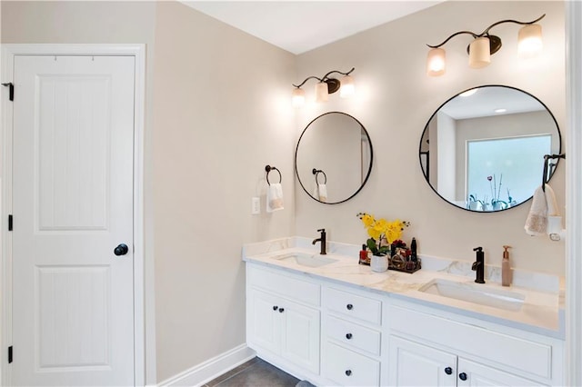 full bath with double vanity, baseboards, and a sink