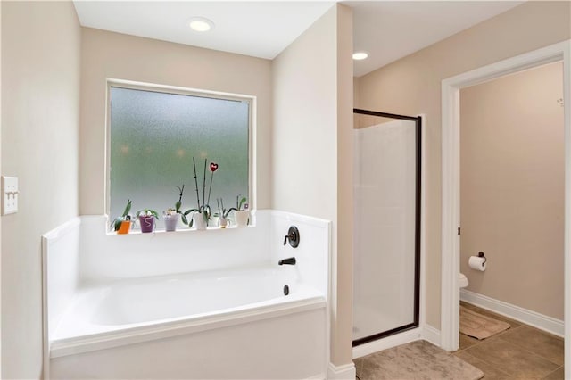 full bathroom with baseboards, tile patterned flooring, a shower stall, a garden tub, and toilet