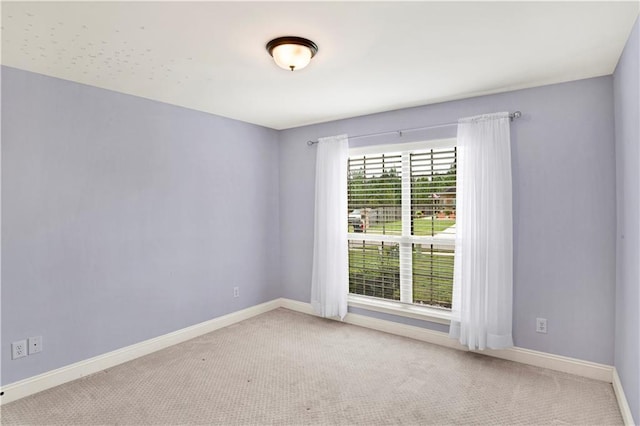 carpeted empty room featuring baseboards