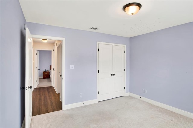 unfurnished bedroom featuring a closet, visible vents, carpet flooring, and baseboards