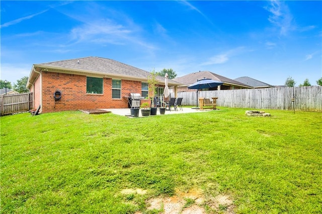 rear view of property with a patio, a lawn, brick siding, and a fenced backyard