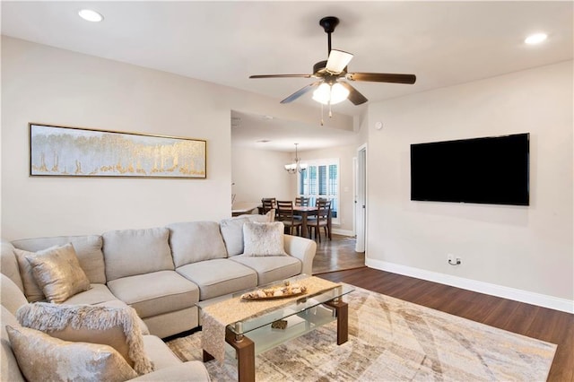 living room with dark wood finished floors, recessed lighting, ceiling fan with notable chandelier, and baseboards