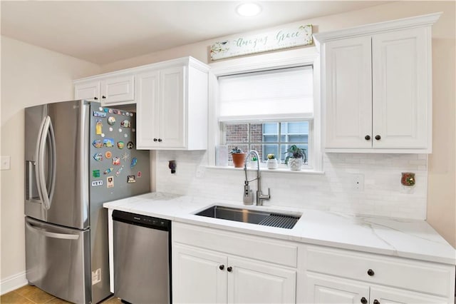 kitchen with decorative backsplash, white cabinets, appliances with stainless steel finishes, and a sink