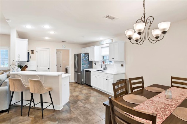 kitchen featuring visible vents, backsplash, a breakfast bar, stainless steel appliances, and a sink