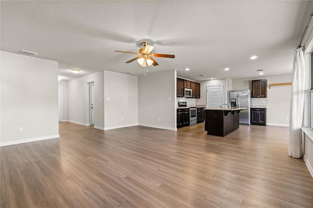 living area featuring a ceiling fan, visible vents, baseboards, and wood finished floors