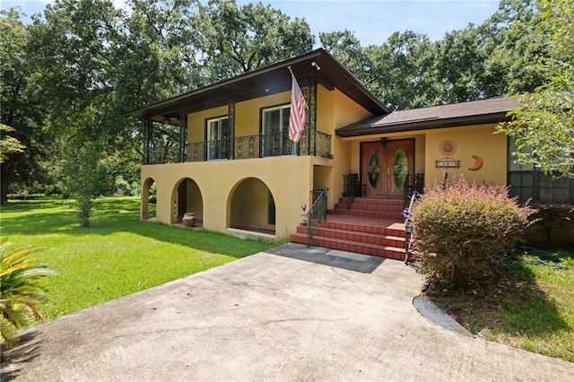 view of front of house with a balcony and a front lawn