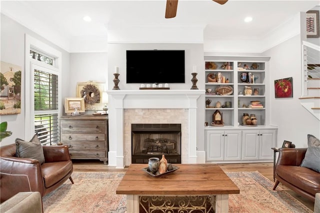 living area with crown molding, ceiling fan, and light hardwood / wood-style flooring