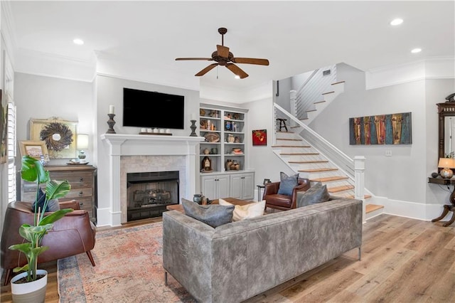 living room with light hardwood / wood-style flooring, ornamental molding, and ceiling fan