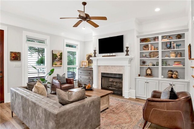 living room featuring light hardwood / wood-style flooring, ornamental molding, and ceiling fan