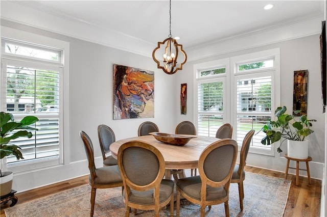 dining space with hardwood / wood-style flooring, crown molding, and an inviting chandelier