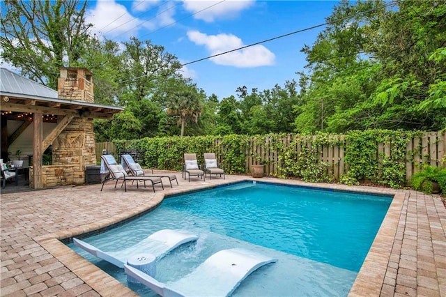 view of pool with a patio and an outdoor stone fireplace