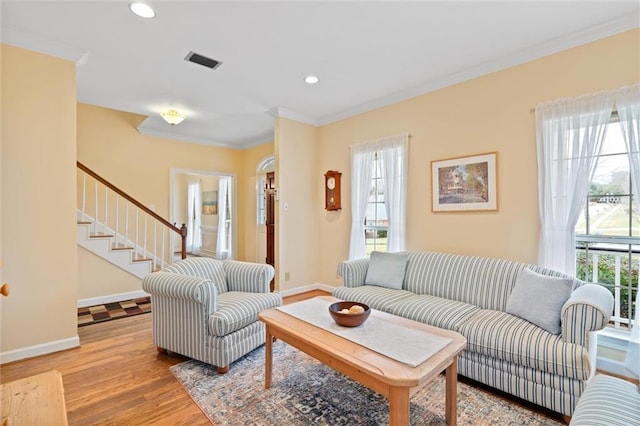 living area with visible vents, ornamental molding, light wood-style floors, and baseboards