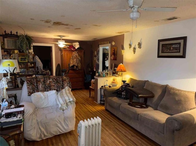 living room with hardwood / wood-style flooring, ceiling fan, and radiator heating unit