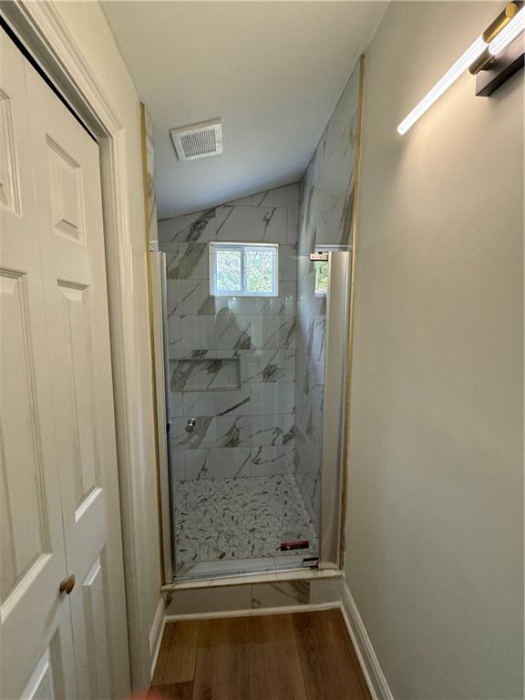 bathroom with a tile shower and hardwood / wood-style floors